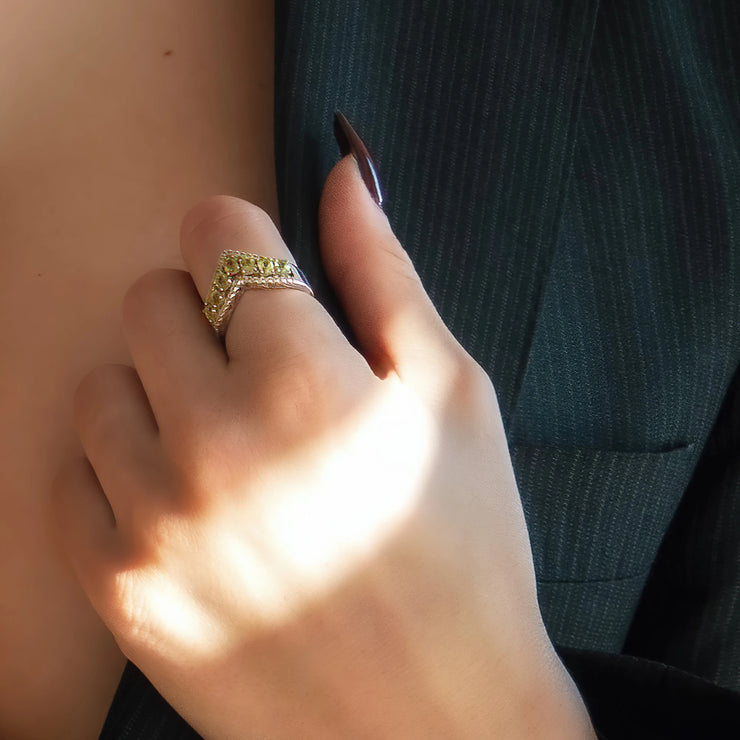 An everyday sterling silver ring featuring natural green peridot gemstones on a model&
