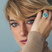 Close-up of a model's hand wearing an exclusive sterling silver ring adorned with natural Swiss blue topaz stones